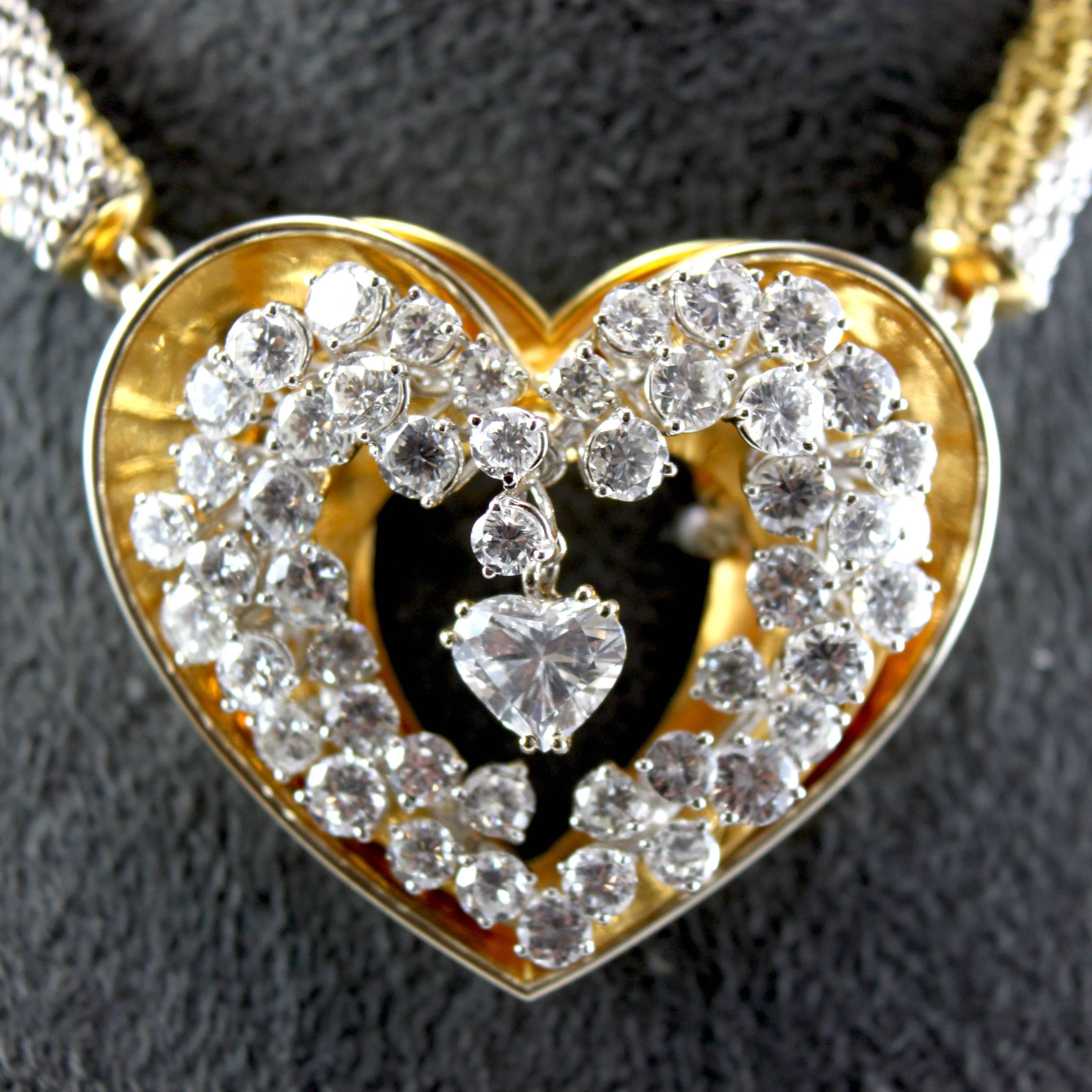 A loving 18k yellow and white gold diamond heart pendant, by ME Riedel.

Centring a heart-shaped diamond of ca. 1.15 carats (D-F/VS2), 
surrounded by a moving heart-shaped cluster of diamonds of ca. 9 carats and 
set on a heart-shaped gold