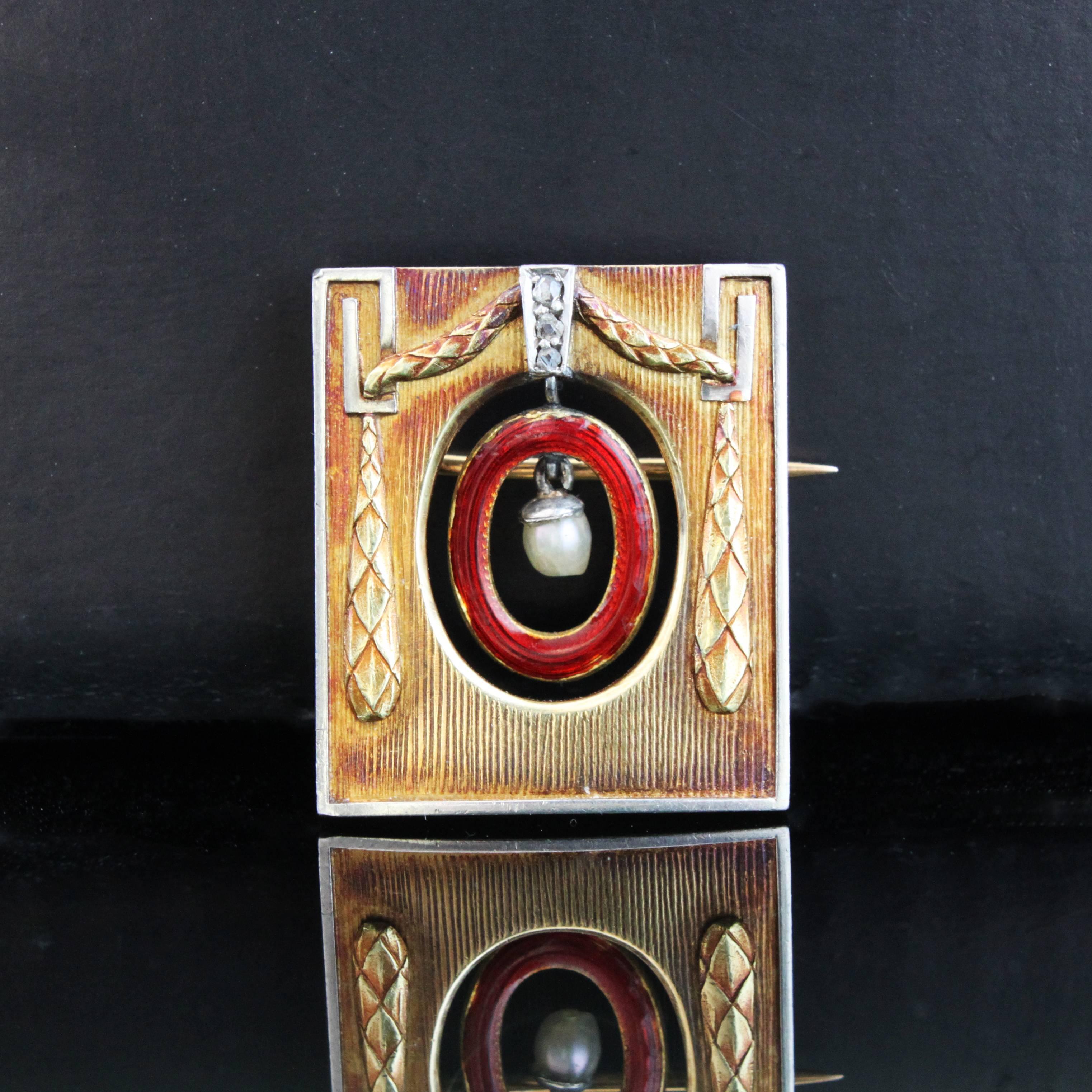 A beautiful and rare 18k gold brooch by Theodor Fahrner, in a rectangular gateway design, with a pearl and a red enamelled ring around it in the center, hinged to a diamond-set column and surrounded by curtain-shaped gold work.

Theodor Fahrner