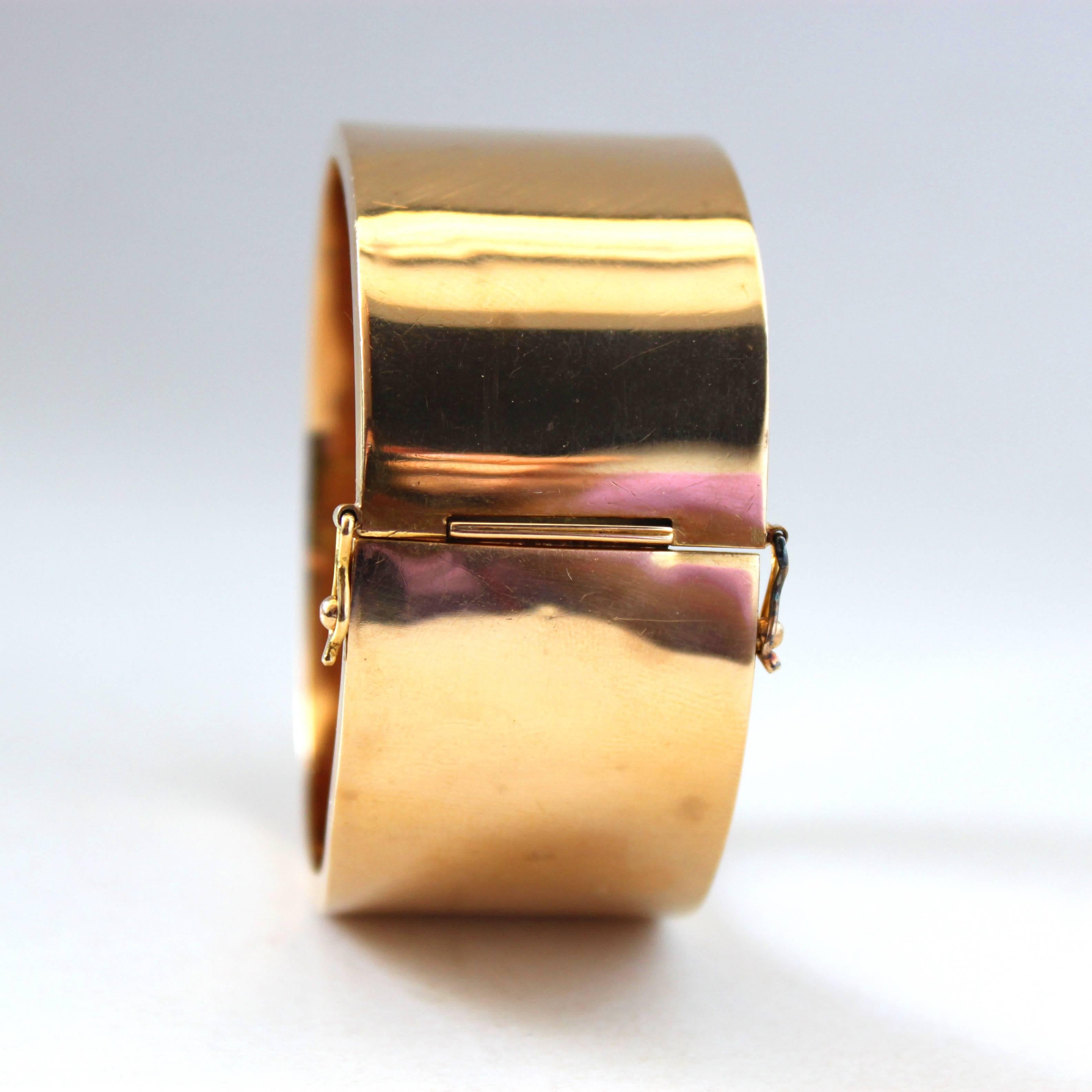 A very chic 18k gold bangle, ca. 1960s.

The sleek hinged gold bangle is made of 18k yellow gold. The gold's texture is very shiny and reflective. A beautiful accessory for any lady.

Circumference ca. 16.5cm (6.5 in)