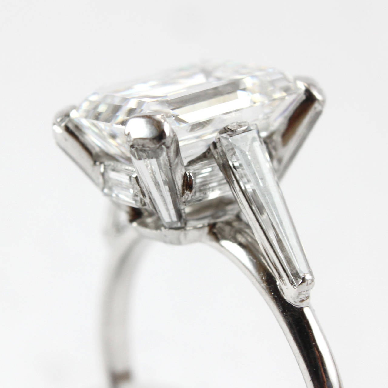A solitaire ring with a beautiful 4.20ct GIA certified emerald cut diamond. It is very unusually surrounded by 10 tapered baguettes throughout the shank and prongs.

Weight: 4.20 carats
Color: E
Clarity: VS1
Fluorescence: none
Cut: