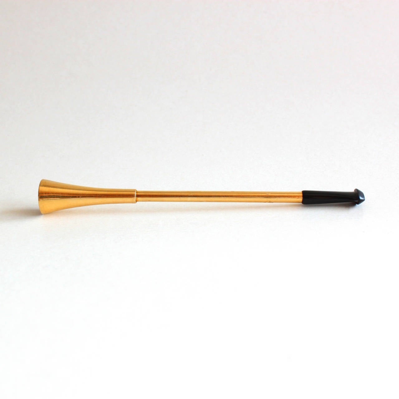 A sleek Art Deco Cartier 18k gold cigarette holder in the shape of a trompete, ending with an onyx mouthpiece. The end of the cigarette holder has a spring to easily mount a cigarette.

Signed, numbered and hallmarked. Cartier Paris 1930s.