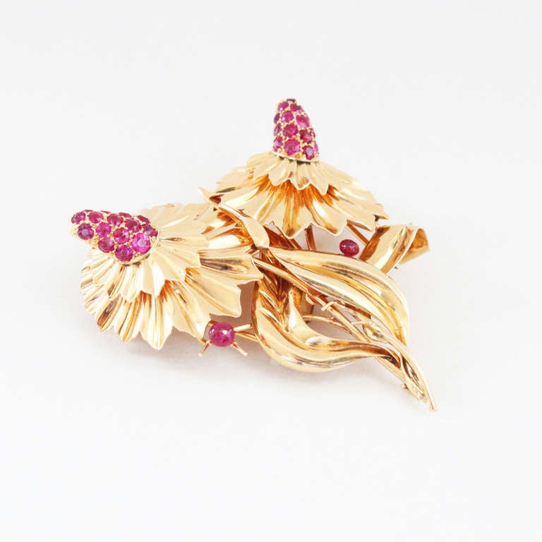 A Retro double clip flower brooch by Mellerio dits Meller, set with natural rubies. It has a beautiful asymmetrical double clip mechanism, which converts the brooch into two single flower brooches. Signed and numbered.
