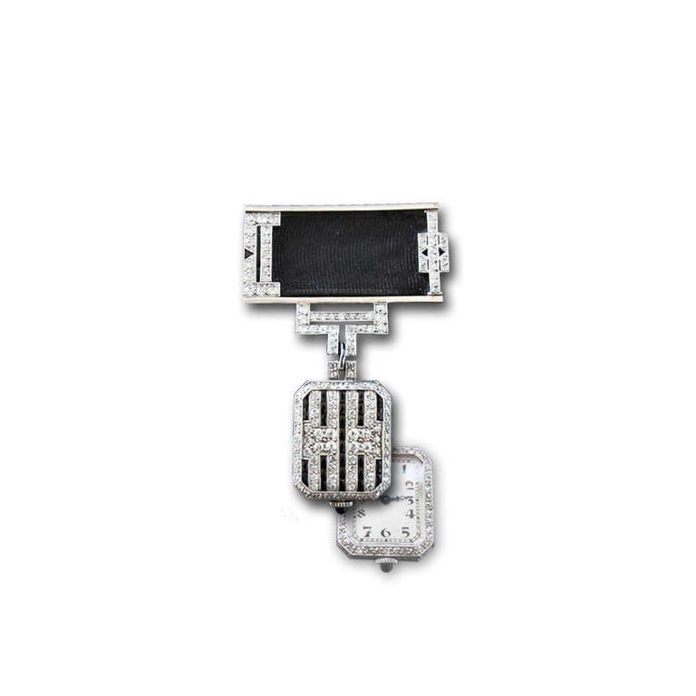 A unique diamond and onyx brooch with a reversible Longines watch, by Moshammer. This brooch has a striking black & white design. The watch is flipped upwards to read the time. It has an inventory number, Moshammer signature as well as its makers