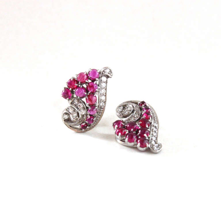 A beautiful Art Deco ruby and diamond earring clips and brooch swirl set, consisting of natural burmese ruby cabochons of circa 7 carats and round diamonds of circa 1.5 carats.

The centrepiece can also be converted into a pin.

Earring