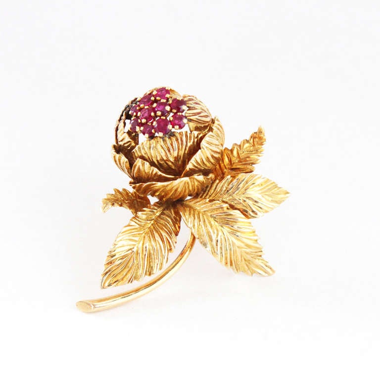 An elegant and sporty flower brooch by Van Cleef & Arpels from 1950s-1960s, set with blossoming natural rubies in 18k yellow gold. Signed and numbered.