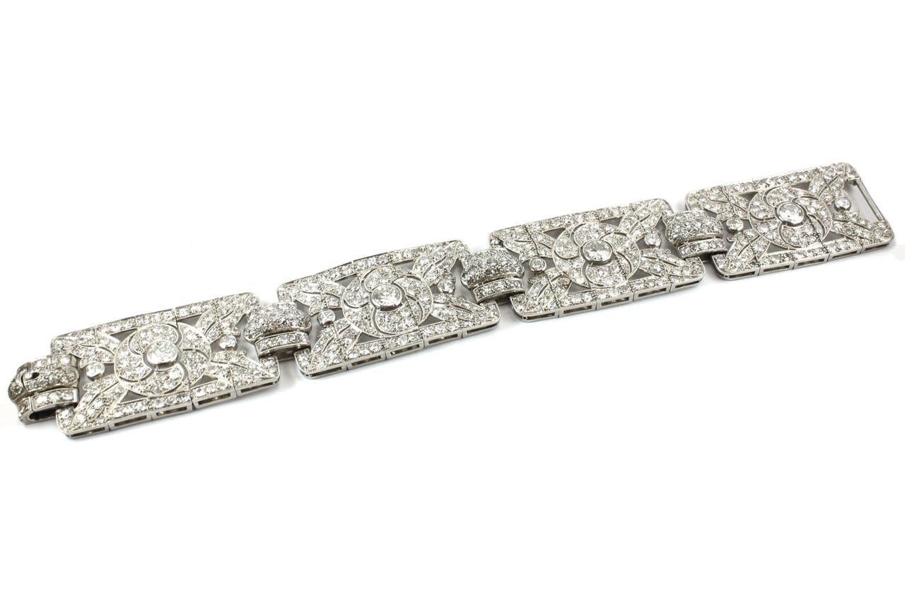 A beautiful early Art Deco floral diamond bracelet in platinum, 1920s. It is designed with 4 broad petals, each set with a big central diamond solitaire, circa 0.8 carats each, F/G colour and VS-SI clarity. The remaining round diamond solitaires