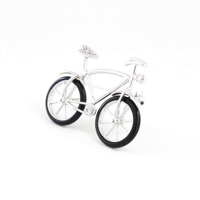 A contemporary and simple gold bicycle brooch with detailed onyx tires that move.