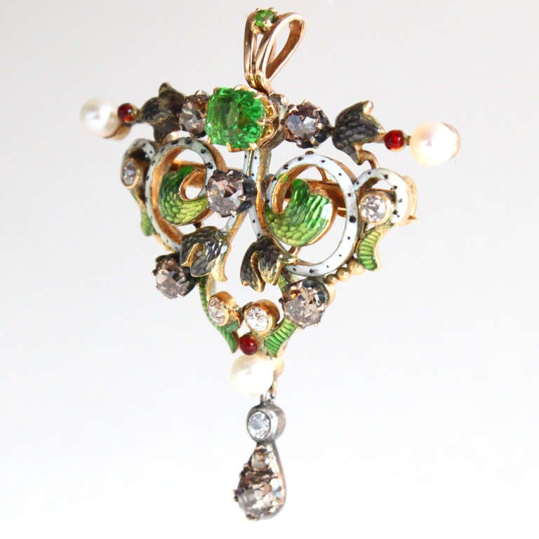 Beautiful Art Nouveau Pendant/Brooch with a central Russian Demantoid accentuated by Pearls and Diamonds, which are marvellously combined with very pretty green, white and greyish/black Enamel work. This lovely jewellery piece can be worn as a