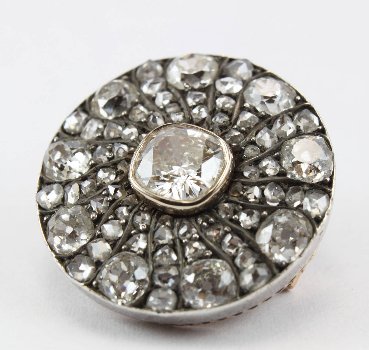 Victorian diamond brooch with a circular design and set with old cut and rosecut diamonds, 1880s. The centre diamond weighs ca. 1.6ct and is of K-L colour and VVS2-VS1 clarity. The remaining 9 old cut diamonds weigh a total of ca. 3cts. The brooch