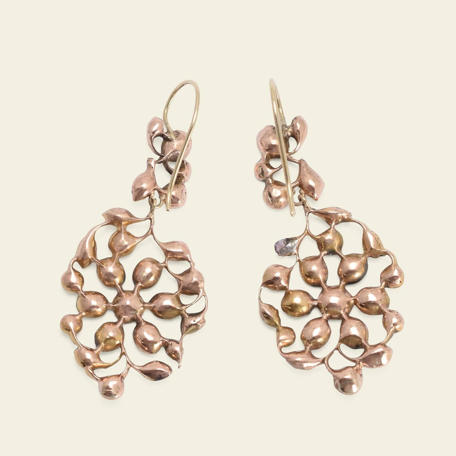 These Georgian earrings are modeled in 10k gold in a beautiful swirling floral motif. The exquisitely mirrored pendant drops are set with flat cut foil-backed garnets of a lovely purplish red hue.

Materials: 10k gold (tests), foil-backed flat cut