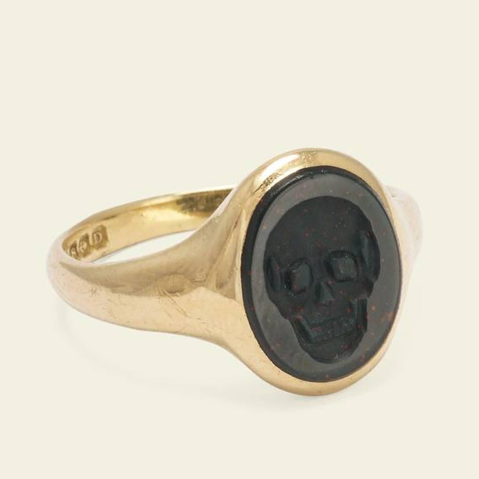 This outstanding signet ring is crafted in 18k yellow gold and bloodstone. The ring features a beautifully carved skull intaglio with smooth contours and a lovely sense of depth. The use of skull imagery is a bit unusual for the time this piece was