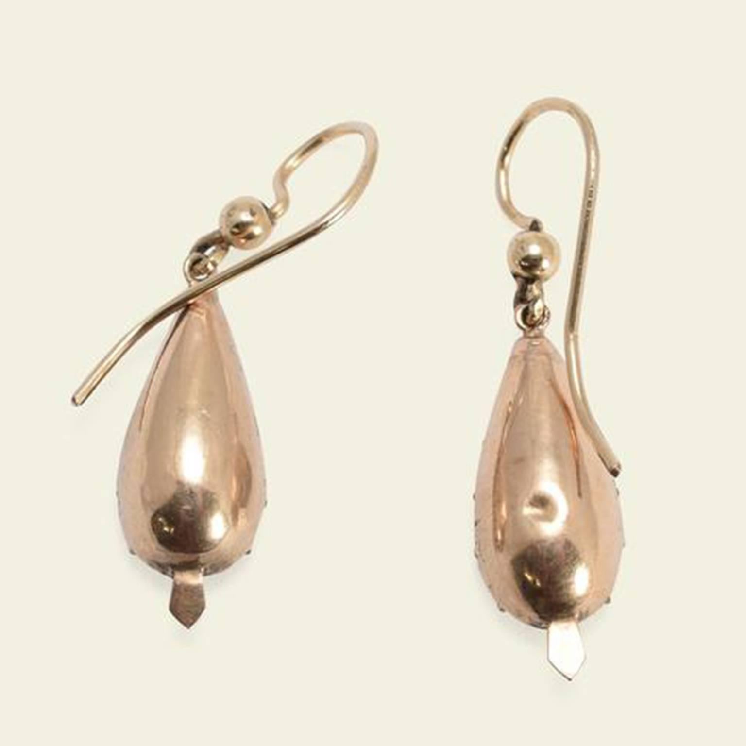 These magnificent Georgian earrings feature elongated pear-shaped citrines with red foil backs. The gemstones are mounted in 15k yellow gold dished settings with crimped edges and a decorative pointed tab at the base. Likely once part of a more