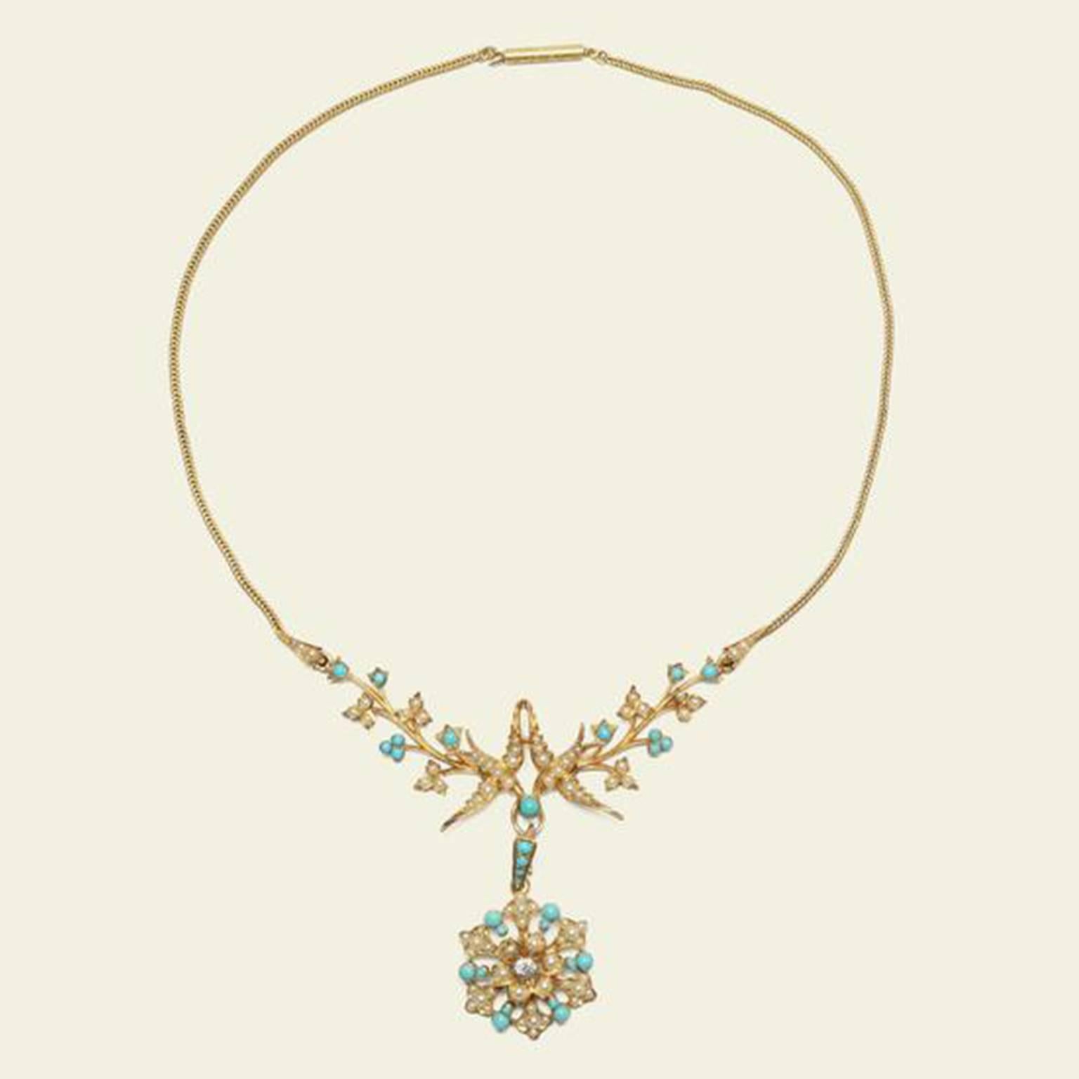 This spectacular Victorian necklace is fashioned in 15k yellow gold and studded with turquoise and seed pearls. Two lovebirds extending from foliate gold branches meet at the center of the necklace, from their joined beaks hangs an exquisite