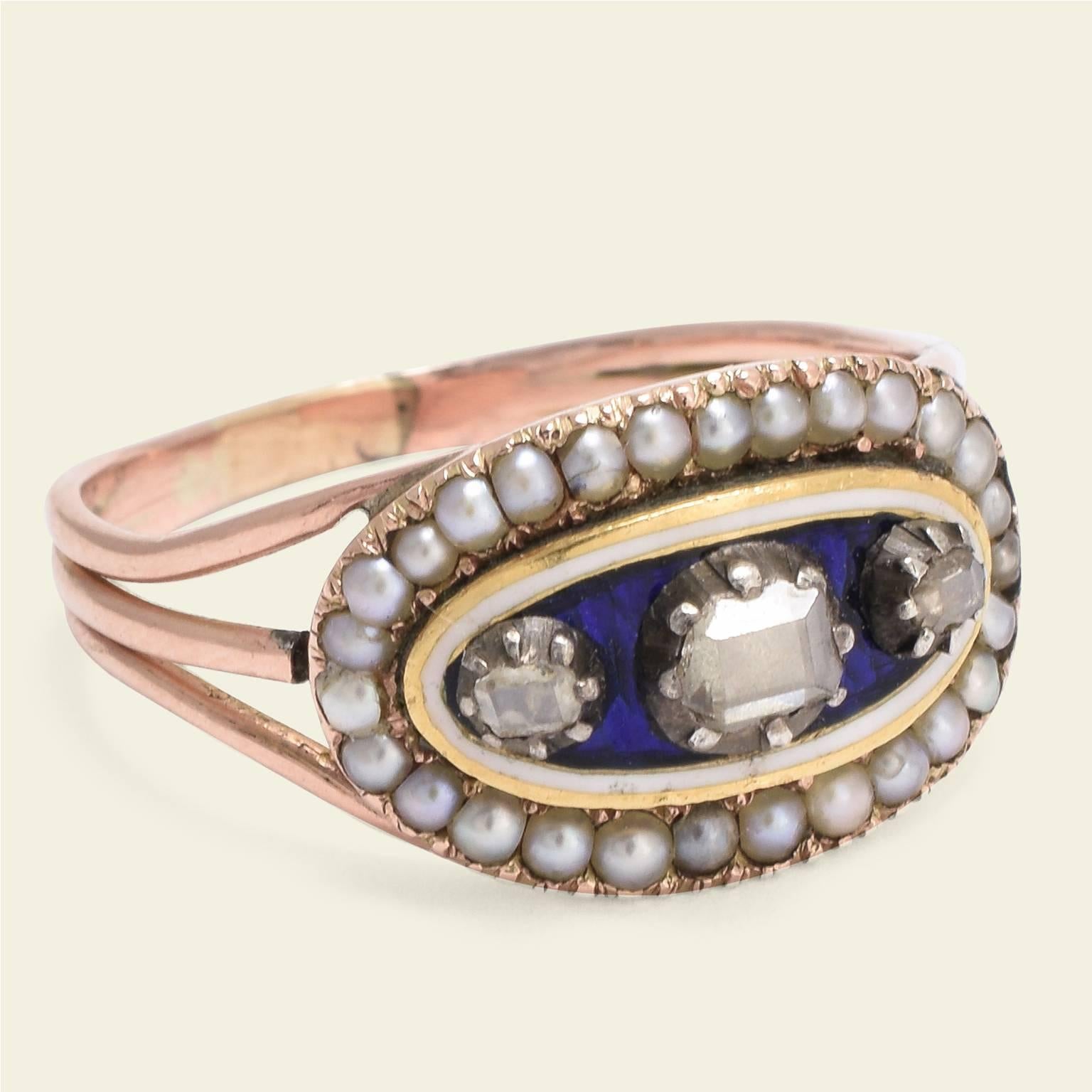 This Georgian ring is a beautiful example of early nineteenth century workmanship. The oval face of the ring features a royal blue center panel punctuated with three table cut diamonds haloed in white enamel and seed pearls. Rings such as this were