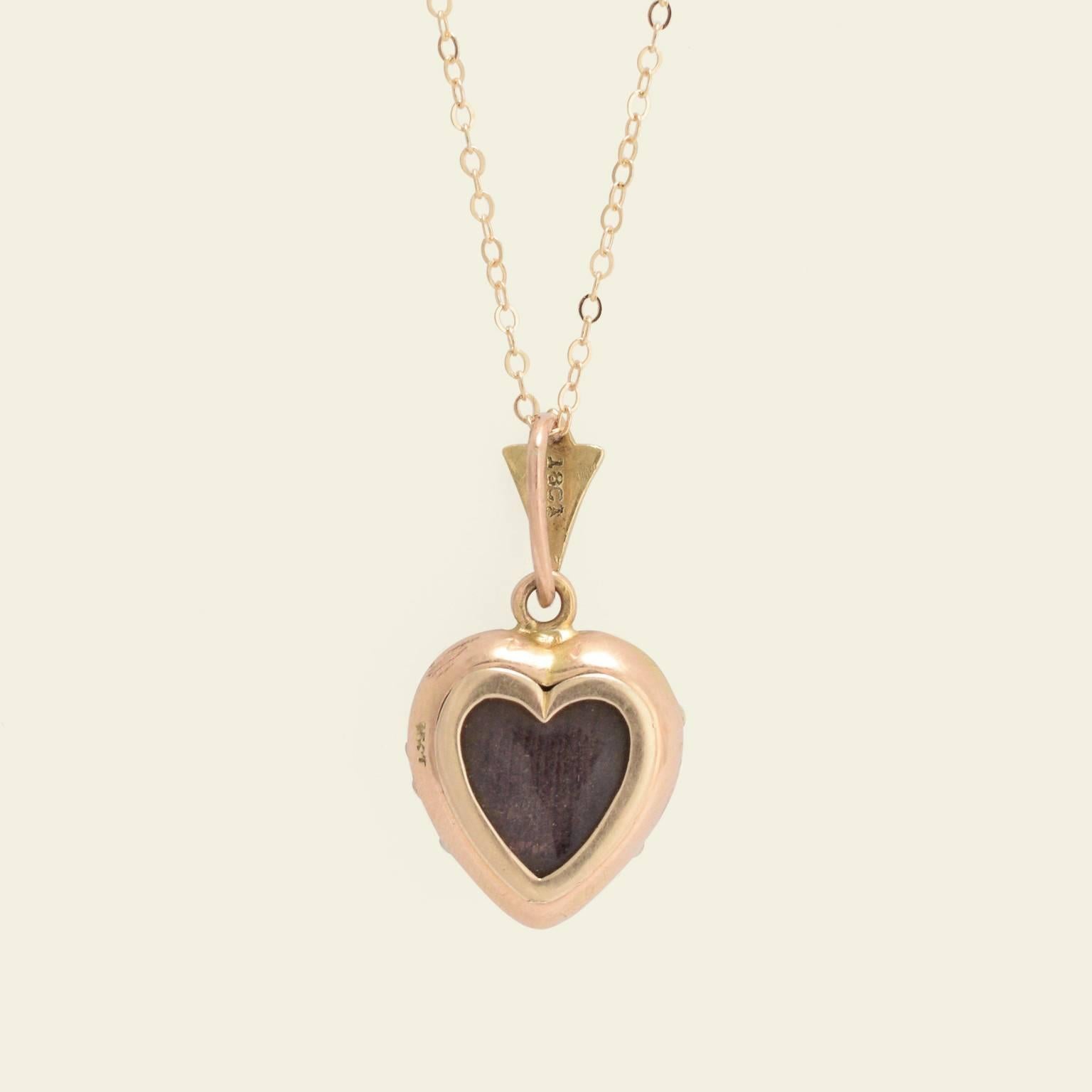 This pretty Victorian heart locket is fashioned in 18k yellow gold and dates to the 1880s. The locket and the fancy bail it hangs from are pavé set with lustrous white seed pearls. The reverse side features a glass-fronted locket which can easily be