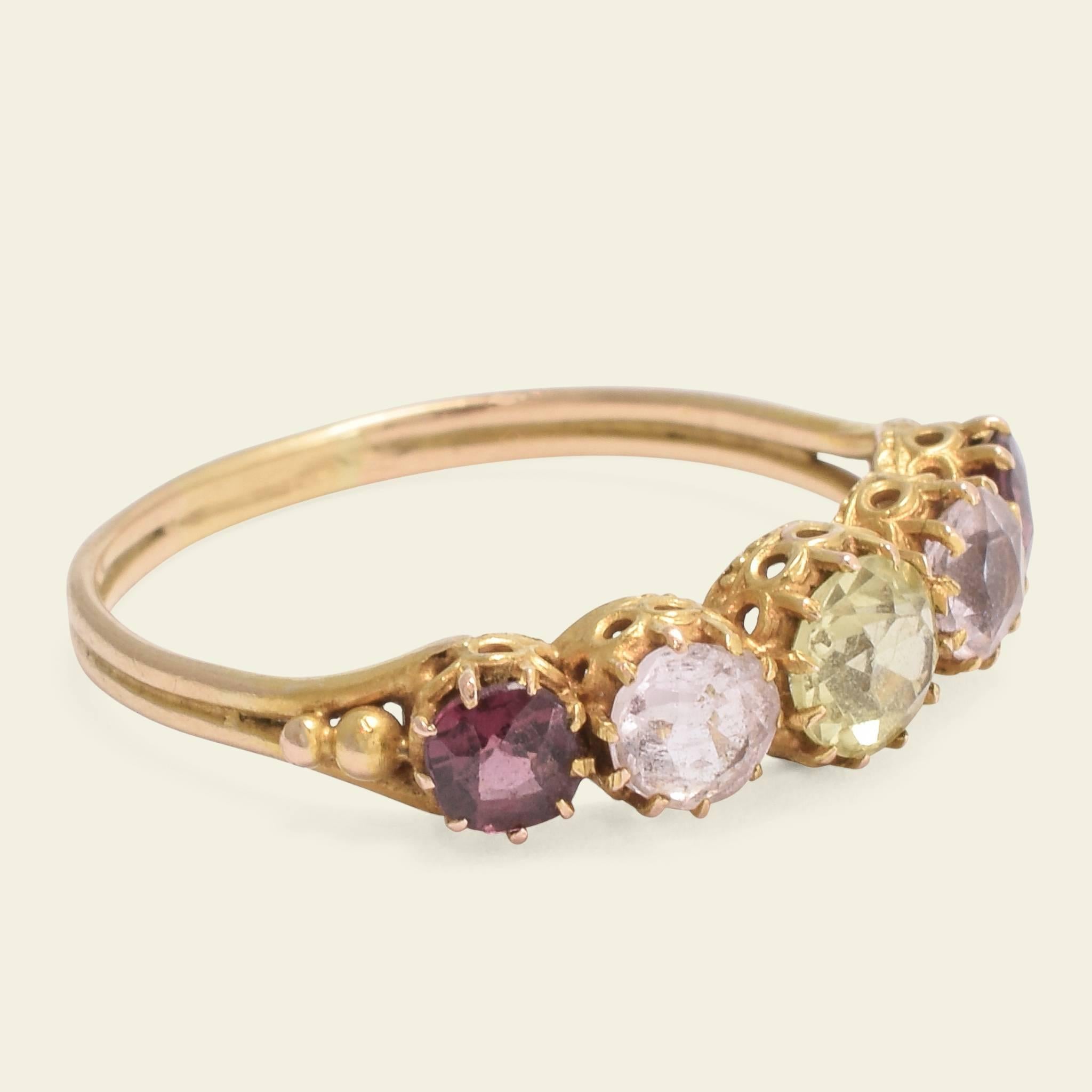 This pretty multi-colored five stone ring is fashioned in 18k yellow gold and dates to the mid Victorian period. The ring is set with purplish almandine garnets, ultra pale amethysts, and a single chrysoberyl. The gems are prong-set above a