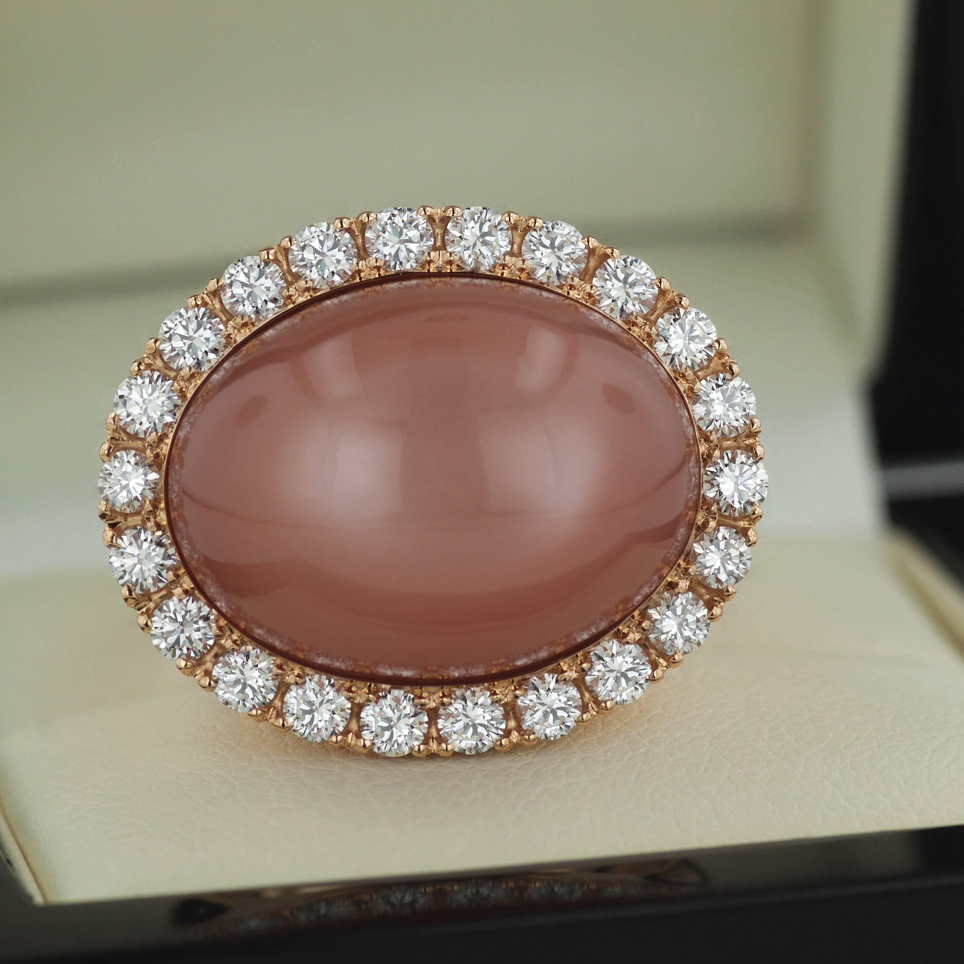 This stunning 18K rose gold women’s fashion ring features a large 22.90-carat rectangle moonstone cabochon at the top, surrounded by a halo of sparkling round cut diamonds with a total of 1.76 carat. The masterfully pave set halo adds a brilliant