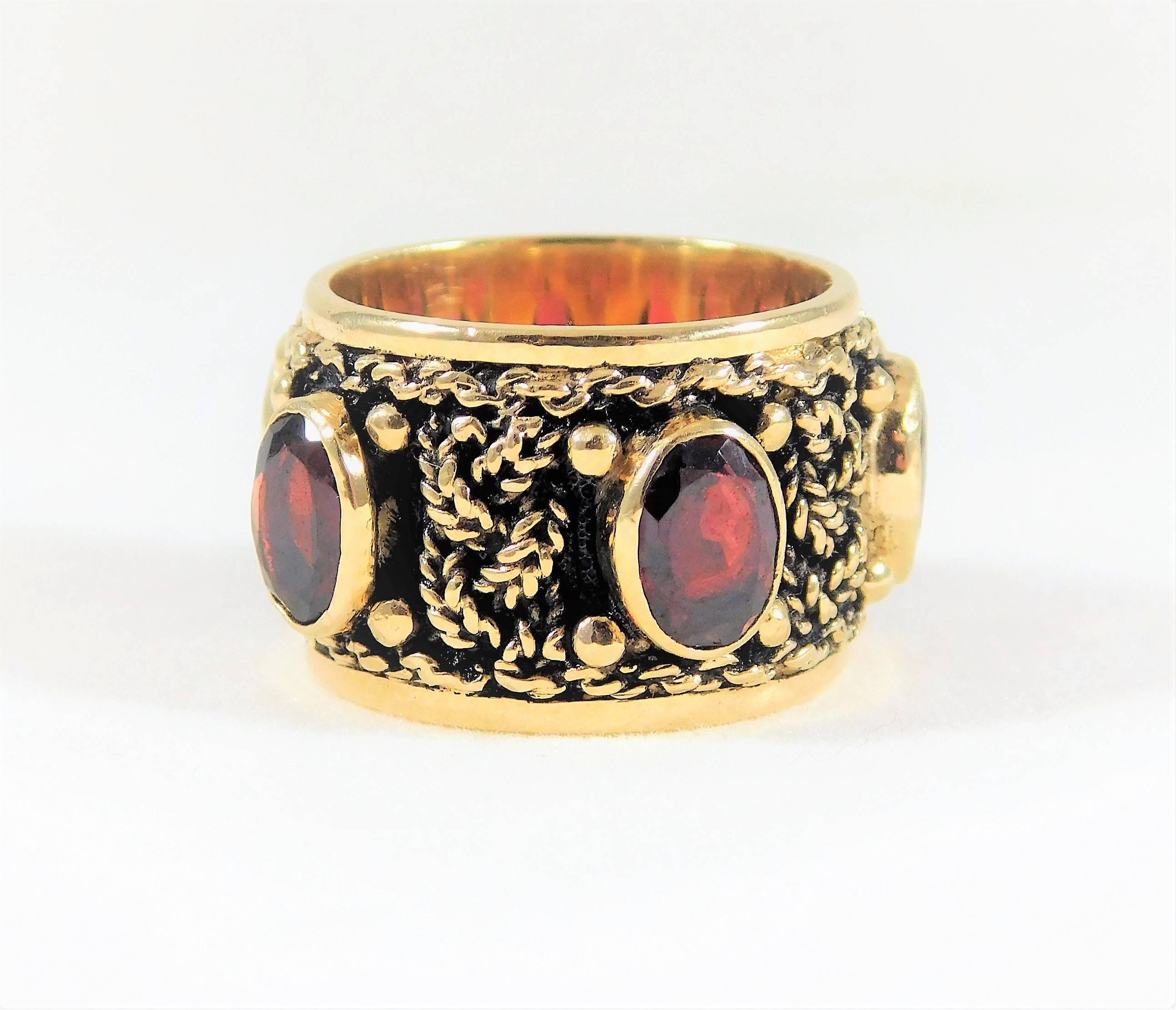 From a noble New Orleans estate.  Circa 1950.  A very unique antique piece! This elegant ring is made of solid 14k yellow gold.  It is a ½ inch wide and weighs 11.8 grams. It is masterfully jeweled with 5 beautiful oval-faceted AAA quality Rhodolite