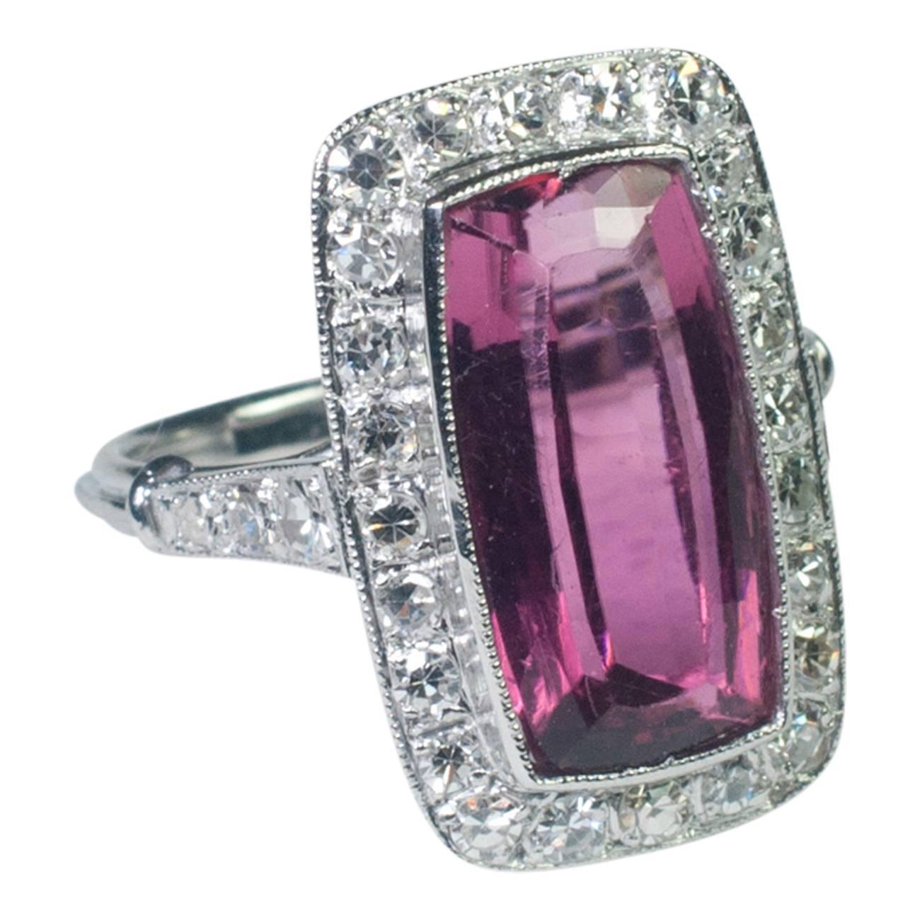 The dark pink tourmaline weighs 4.64ct and is surrounded by 8-cut diamonds and diamond shoulders.  The total diamond weight is 0.84ct.  The ring is mounted on a triple reeded shank and tests as platinum.  Length 1.55cm x width 0.80cm.  Finger size L