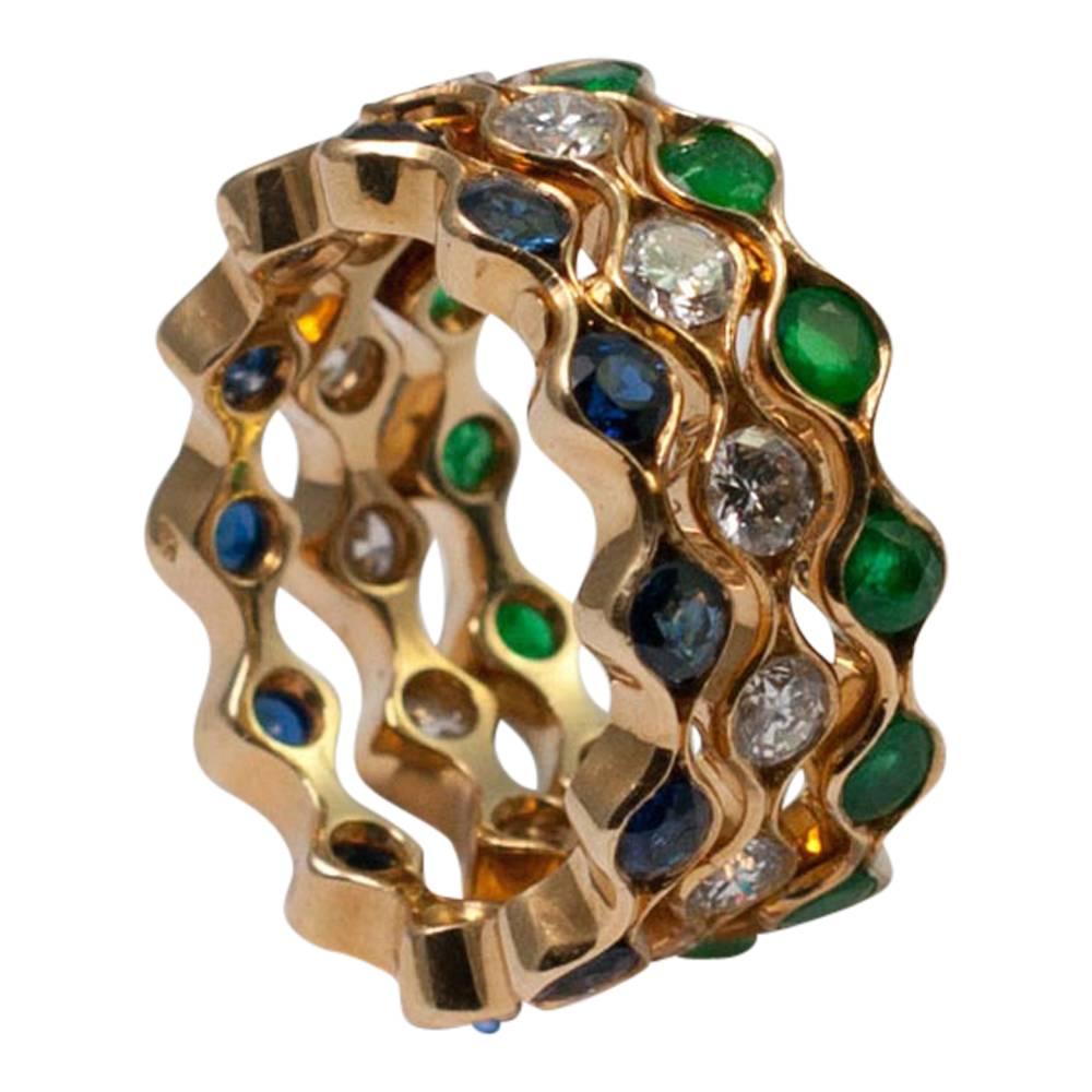 Beautiful and unusual triple eternity ring in 18ct gold; this is formed of three wavy bands that fit together, one set with brilliant cut diamonds, one with royal blue sapphires and one with vibrant green emeralds.  The bands move independently but