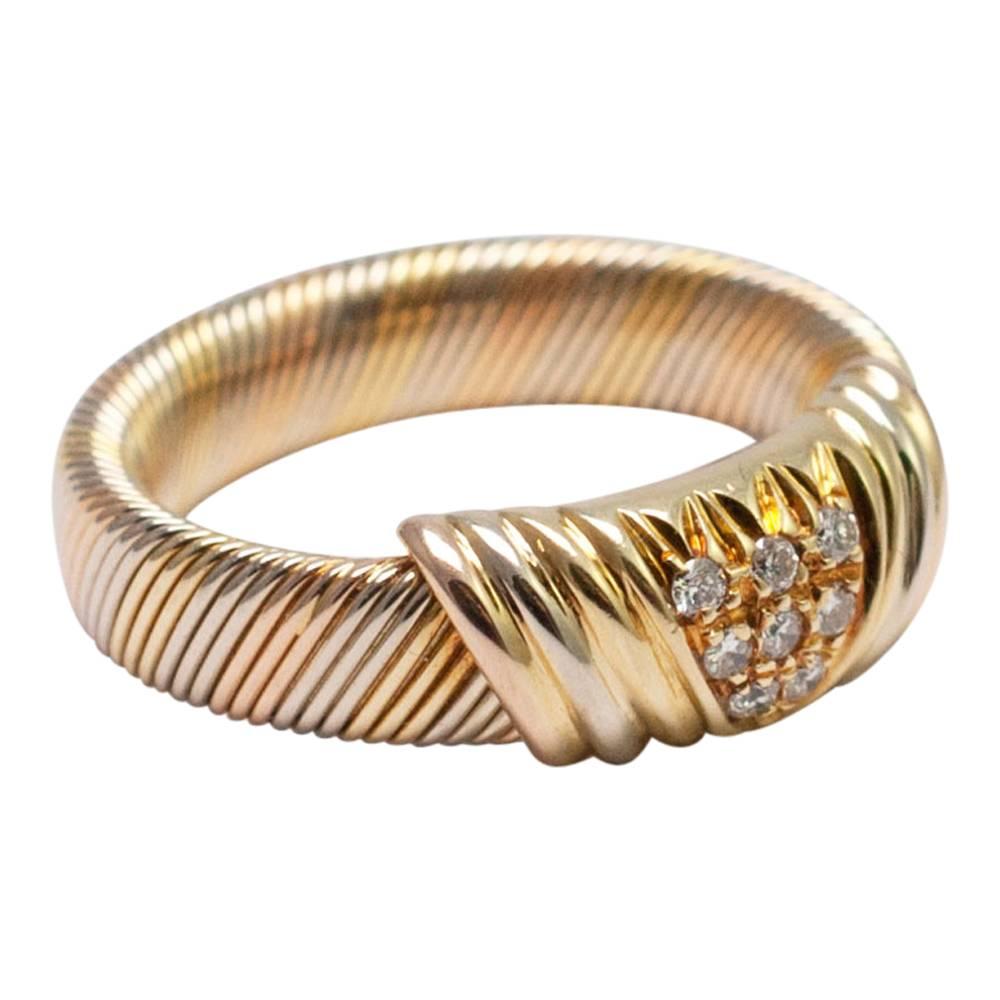 Cartier three colour 18ct gold and diamond band formed of a reeded design creating a wire effect.  There are 8 brilliant cut diamonds in the centre.  Weight 7.7gms.  Numbered, signed Cartier and marked with Swiss control marks for 18ct gold.  Finger