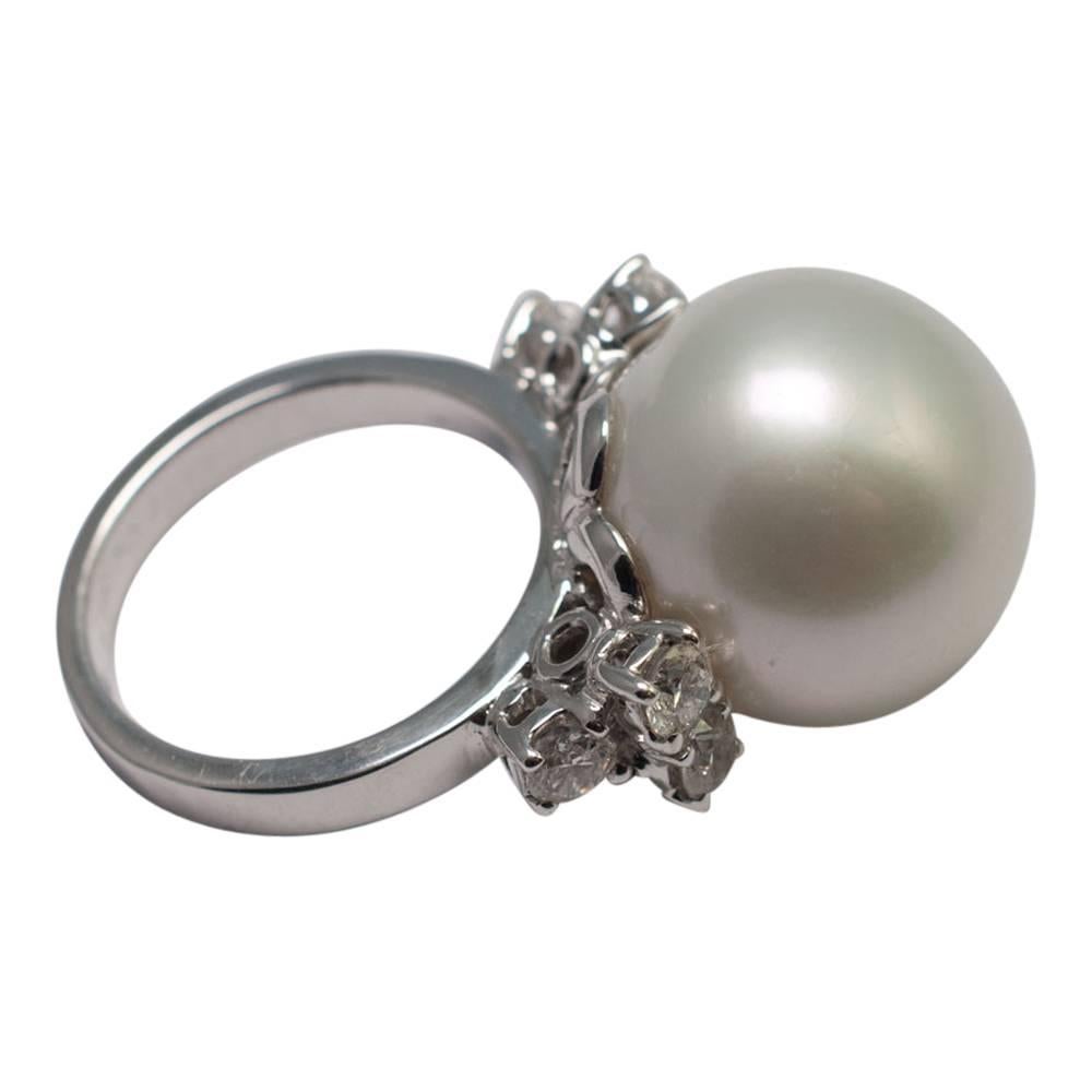 Large, lustrous, white South Sea pearl measuring 16.5mm set with three brilliant cut diamonds on each side weighing approximately 1ct.  The ring is on a solid white band which tests as 18ct gold.  Finger size M (UK), 53 (EU), 6.5 (US).