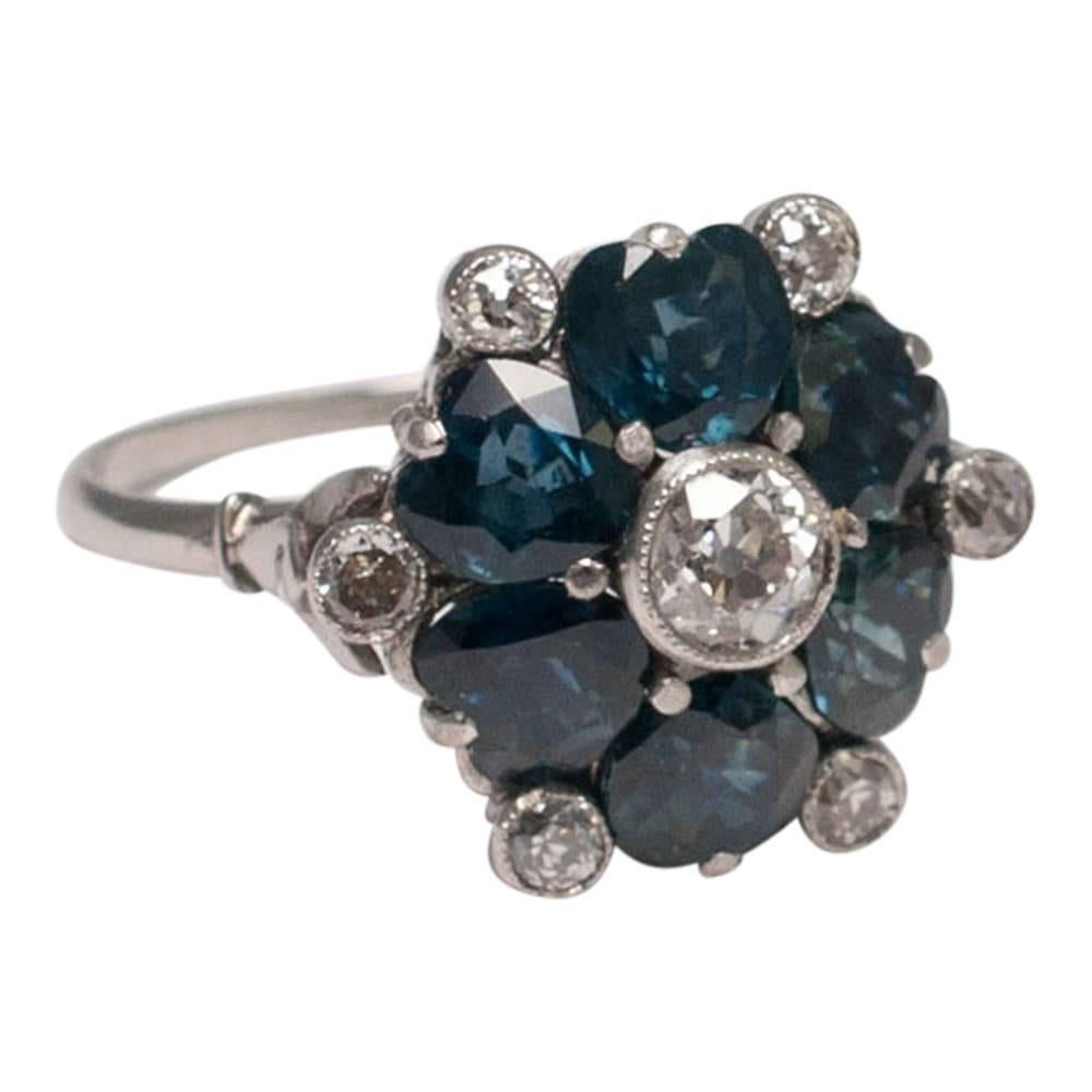 Antique 1920s ring formed of a circle of 6 midnight blue heart shaped sapphires and a central, bezel set Old European cut diamond; around the edge are a further 6 Old European cut diamonds in between the sapphires.  The diamonds weigh 0.60ct, the