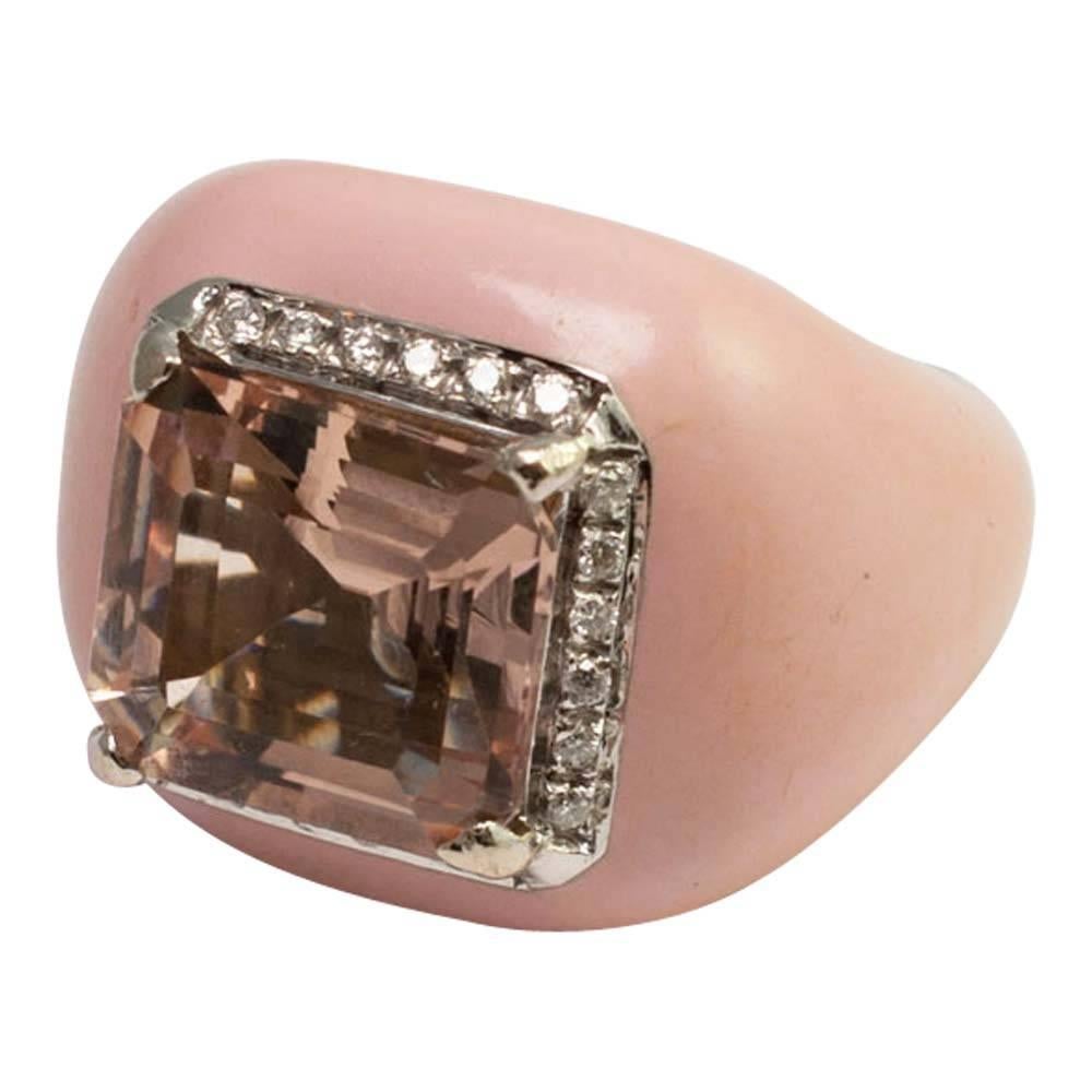 Gorgeous morganite ring for all lovers of the colour pink! This big, bold statement ring is set with a central peachy pink morganite weighing 7.7ct, claw set, and surrounded by 24 brilliant cut diamonds weighing 0.50ct.  The pink enamel is in a pale