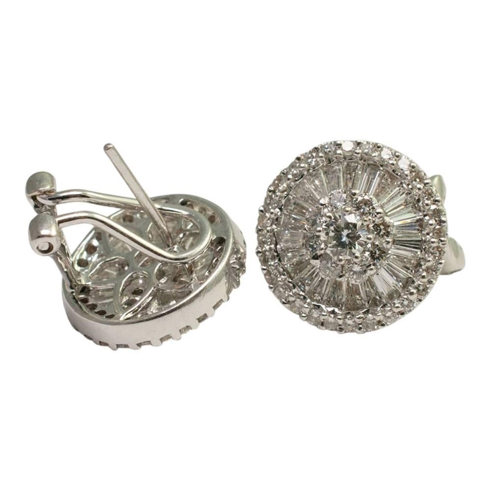 Diamond cluster earrings;  composed of a central brilliant cut diamond surrounded by brilliant cut diamonds, which in turn are surrounded by tapered baguette diamonds and a further row of brilliant cut diamonds round the edge.  These absolutely