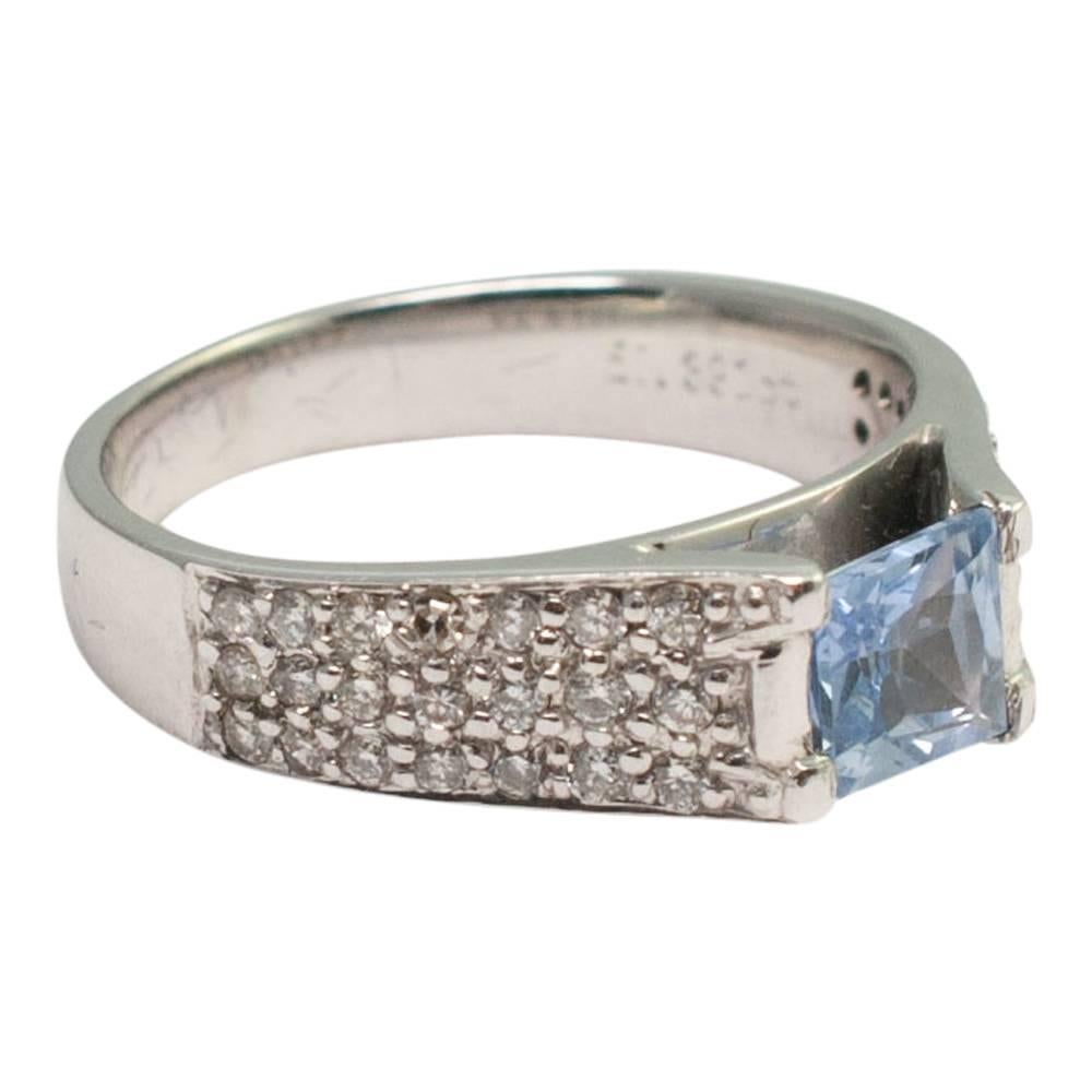 Cool ice blue princess cut sapphire and diamond ring; the sapphire weighs 0.75ct and has three rows of brilliant cut diamonds on either side weighing 0.42ct and covering the half shank.  Tested as 18ct gold.  Weight 5gms.  This ring is in excellent