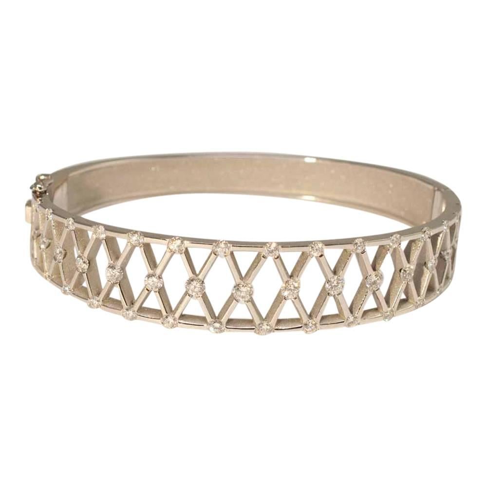 Platinum and diamond bangle forming an openwork lattice design; the brilliant cut diamonds weigh 2.30ct and are set on the sides and crossover sections of the latticework.  The top section of the bangle is fixed to a solid tapering platinum lower