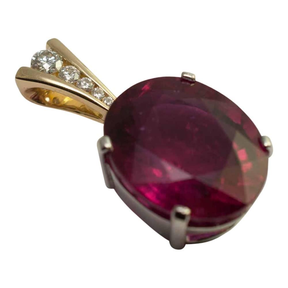 Large rubellite pendant; the stone is a deep raspberry pinkish/red colour and is set with 4 claws in a white gold mount (tested as 18ct).  This is suspended from an articulated yellow bale, channel set with graduated brilliant cut diamonds totalling