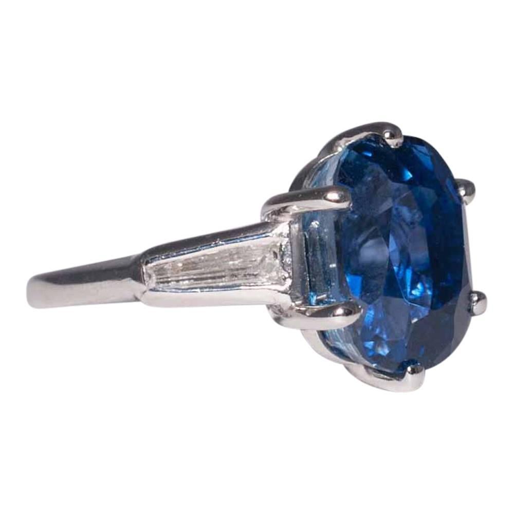 Royal blue sapphire and diamond solitaire ring; the sapphire weighs 9ct and is claw set; on either side there is a graduated baguette diamond set into the shoulders.  The ring is substantial and in solid platinum, weighing 7.7gms. This is a gorgeous