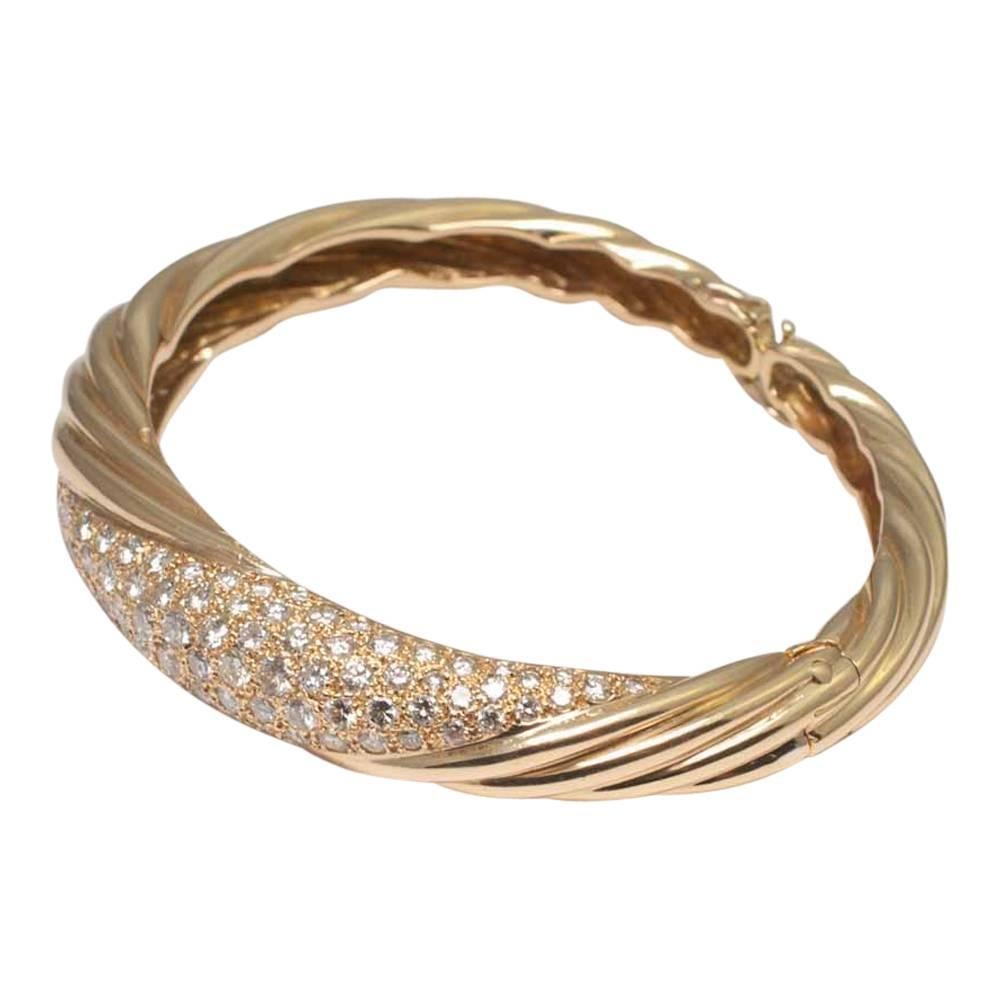 French 18ct gold and diamond bangle; this is formed of diagonal ribbed gold bands with a central diamond set panel, set with 3cts of brilliant cut diamonds.  The bangle opens at the side on a hinge and snaps closed with a spring.  It has a further 2