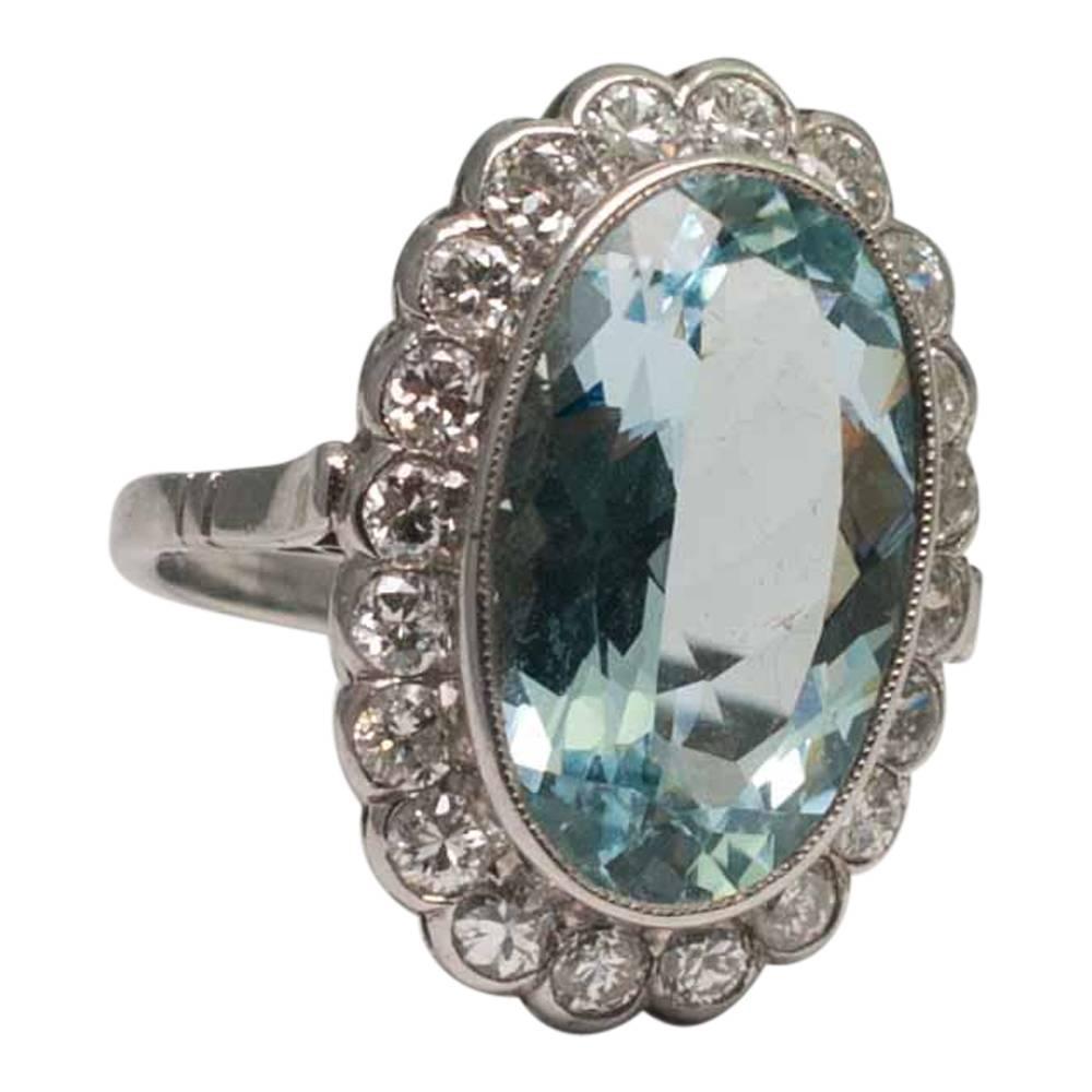 Lovely vintage oval aquamarine and diamond ring; the mixed cut aquamarine weighs 6.85cts and is bezel set, surrounded by transitional cut diamonds weighing a total of 1.40ct. Measuring 2.5cms long x 1.50cms wide, the ring tests as platinum. C.1930.