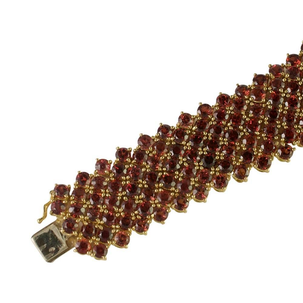 Beautiful garnet and 18ct gold bracelet composed of 7 rows of rich orangey red spessartite garnets weighing a total of 6.50cts.  The bracelet is soft, fluid and feels like ribbon with each stone held by 4 gold claws creating a sparkling effect.  The