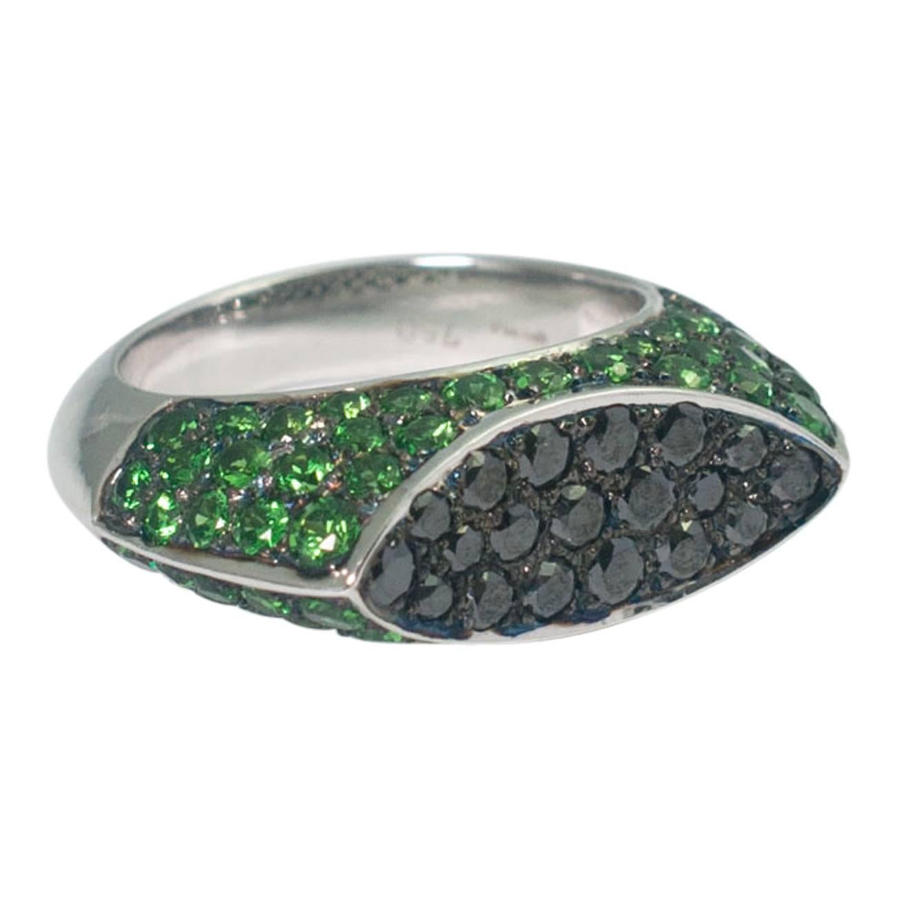 Contemporary ring by exclusive jewellery house, Chatila.  It is formed of a boat shaped design with black diamonds set into blackened gold.  The sides and shoulders are set with vivid green tsavorite garnets.  This unusual ring is stamped 750 and is