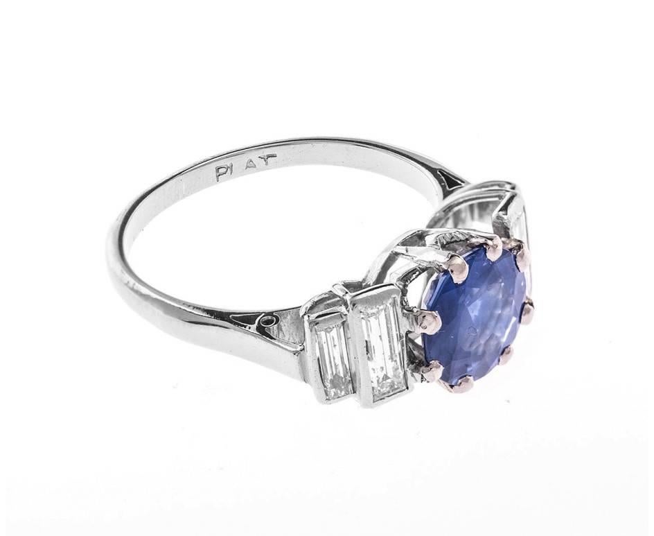 A fabulous Art Deco ring set with baguette cut diamonds creating steps up to a bright blue round faceted sapphire and all crafted in platinum. A stylish engagement ring or a "something old" and "something blue". A perfect gift of