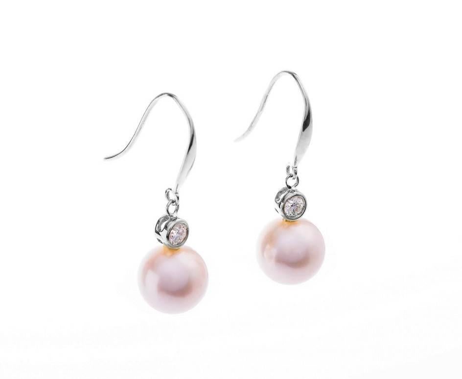 Dropping from a fine white gold wire topped with a scintillating round brilliant cut diamond, these perfect silvery white freshwater pearls are of outstanding quality. With a touch of pink pearlescence, these would make a stunning pearl occasion