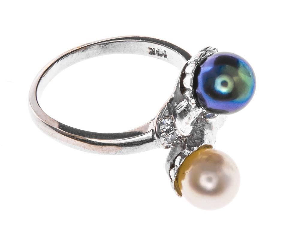 With lily-pad designs cupping a black Tahitian and cream Akoya pearl, the green and pink over tones emanate the sun and sky reflecting off the waters surface. Diamond accents twinkle away like stars adding to the gentle beauty of this ring. The