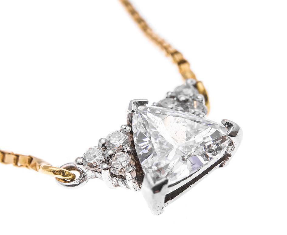 A sparkling trilliant cut diamond with a trefoil of round brilliant cut diamonds on either side crafted in white gold and supported by a sleek yellow gold box chain (42.8cm). This is a wonderful gift for a diamond occasion, an April birthday or a