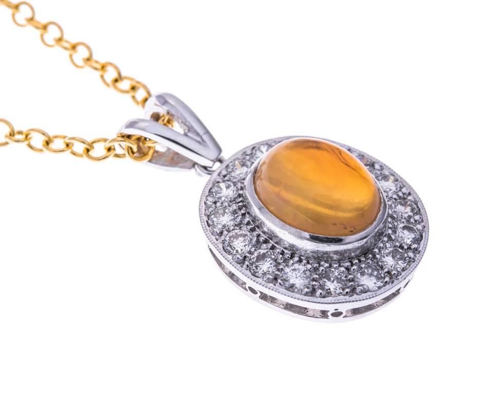 A sparkling diamond halo surrounding a rich orange cabochon fire opal all wrapped up in 18ct cool white gold. This gorgeous pendant is British made and will make a wonderful gift for an October birthday.