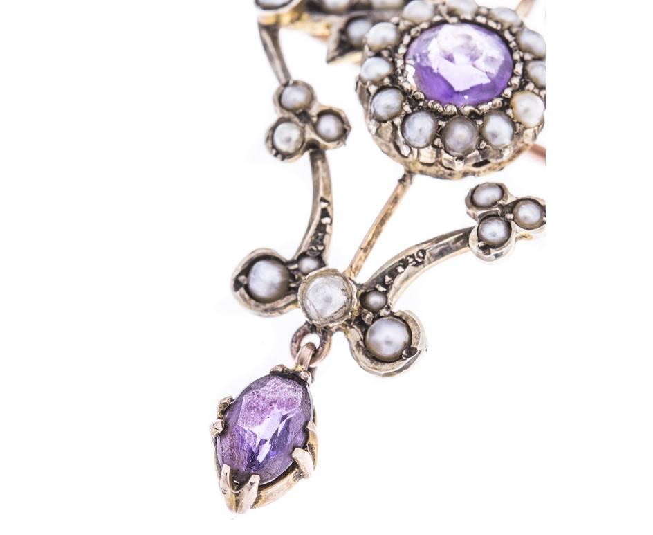 An antique trinket of opulence and Edwardian elegance. This beautiful pendant is fashioned from 9ct gold (as tested) and is delightfully embellished with split pearls and amethyst. It has a pin on the back enabling it to be worn as a brooch.
