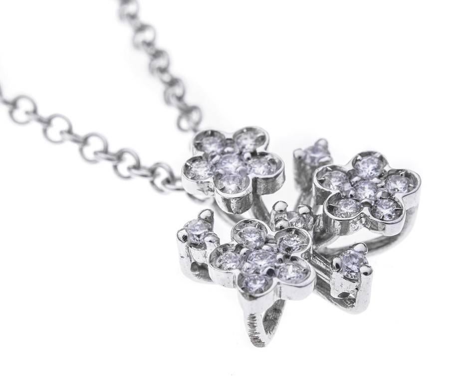 This gorgeous necklace comprises of an 18ct white gold sleek trace link chain adorned with heart shaped spacers and a delicious diamond set floral cluster pendant. The clasp is also embellished with a blue sapphire cabochon for a touch more opulence
