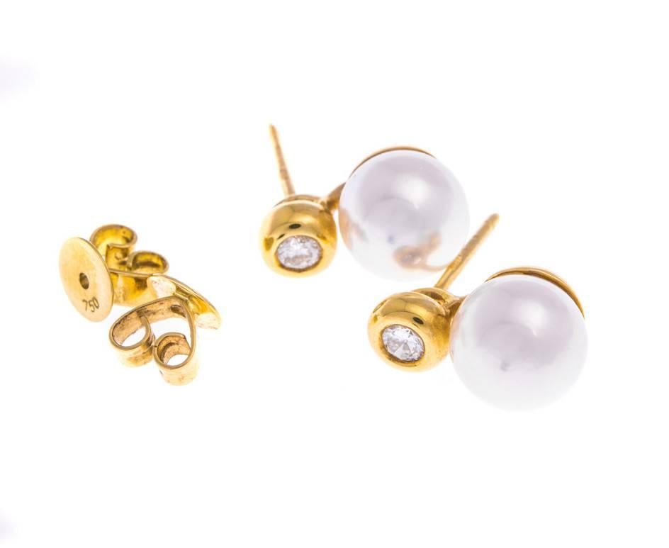 Shimmering with pink and green iridescence these delicious glowing cultured pearls are mounted on bright yellow gold and accentuated with sparkling diamonds. A perfectly elegant pair of stylish pearl studs for every day wear or to add a little shine