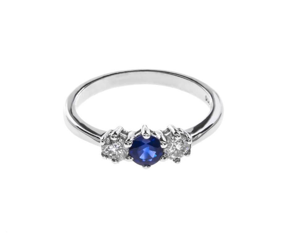 This stylish trilogy ring showcases a beautiful royal blue round faceted sapphire with a sparkling brilliant cut diamond on either side. Lovingly crafted in 18ct white gold it's an ideal adornment to choose for a classic engagement ring or give as a