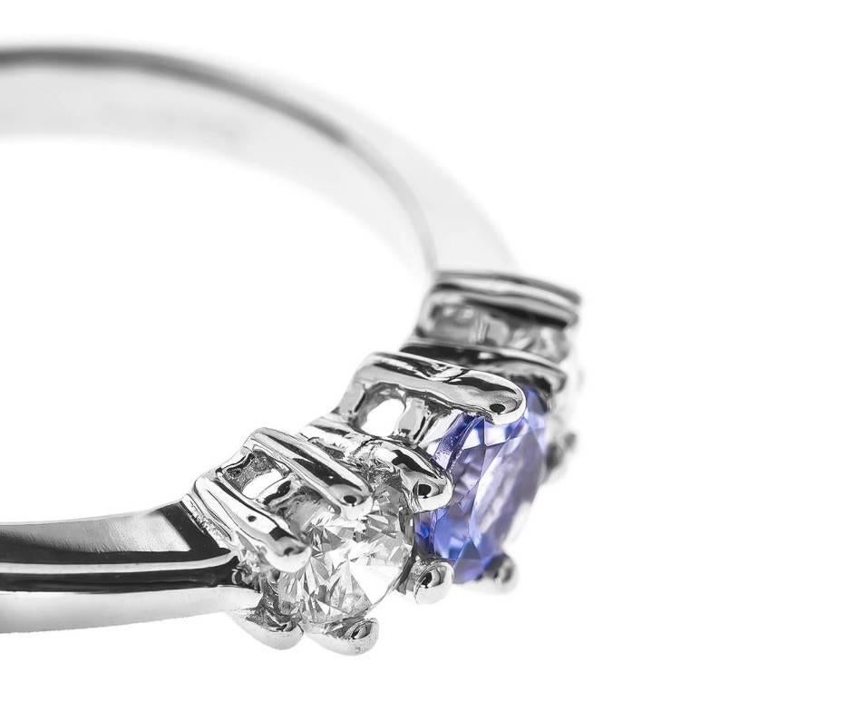 This stylish trilogy ring showcases a delicious purple round faceted tanzanite with a bright brilliant cut diamond on each side. Fabulously fashioned in 18ct white gold it's a wonderful piece for a December birthday or a beautiful twist on the