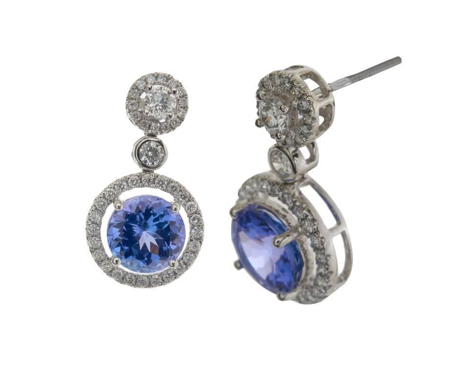 Delicious and opulent tanzanites with intense tones of purple and blue framed in halos of sparkling diamond and crafted in cool white gold. These fabulous Deco style drop earrings are a wonderful addition to any jewel box. A lavish and colourful