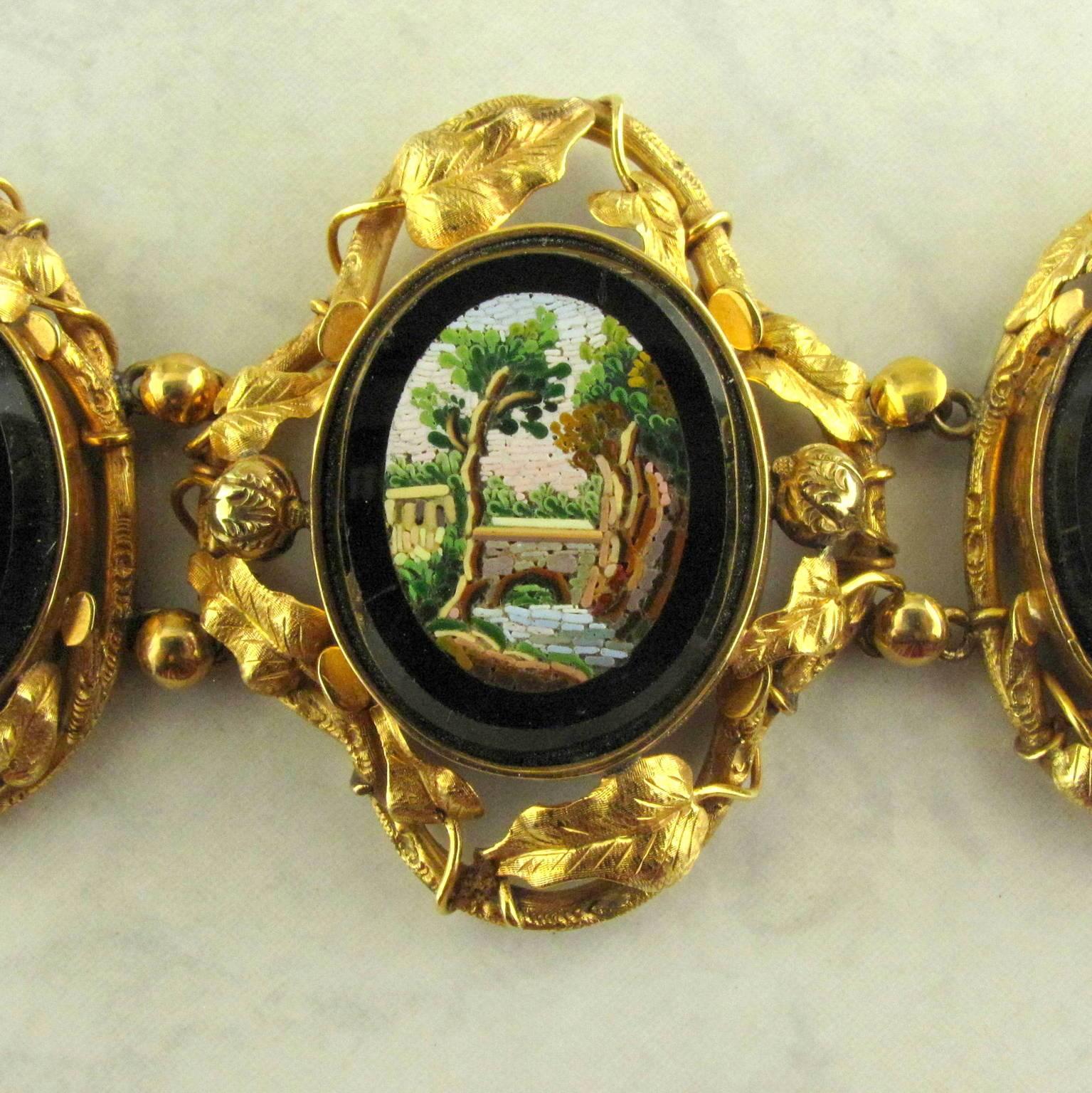 14 karat yellow gold Victorian micro mosaic bracelet.
The antique bracelet consisting of five linked sections of onyx with micro mosaic shields in trailing leaf motif  frames depicting water scenes.  Measuring  1.50 at its widest and tapering down