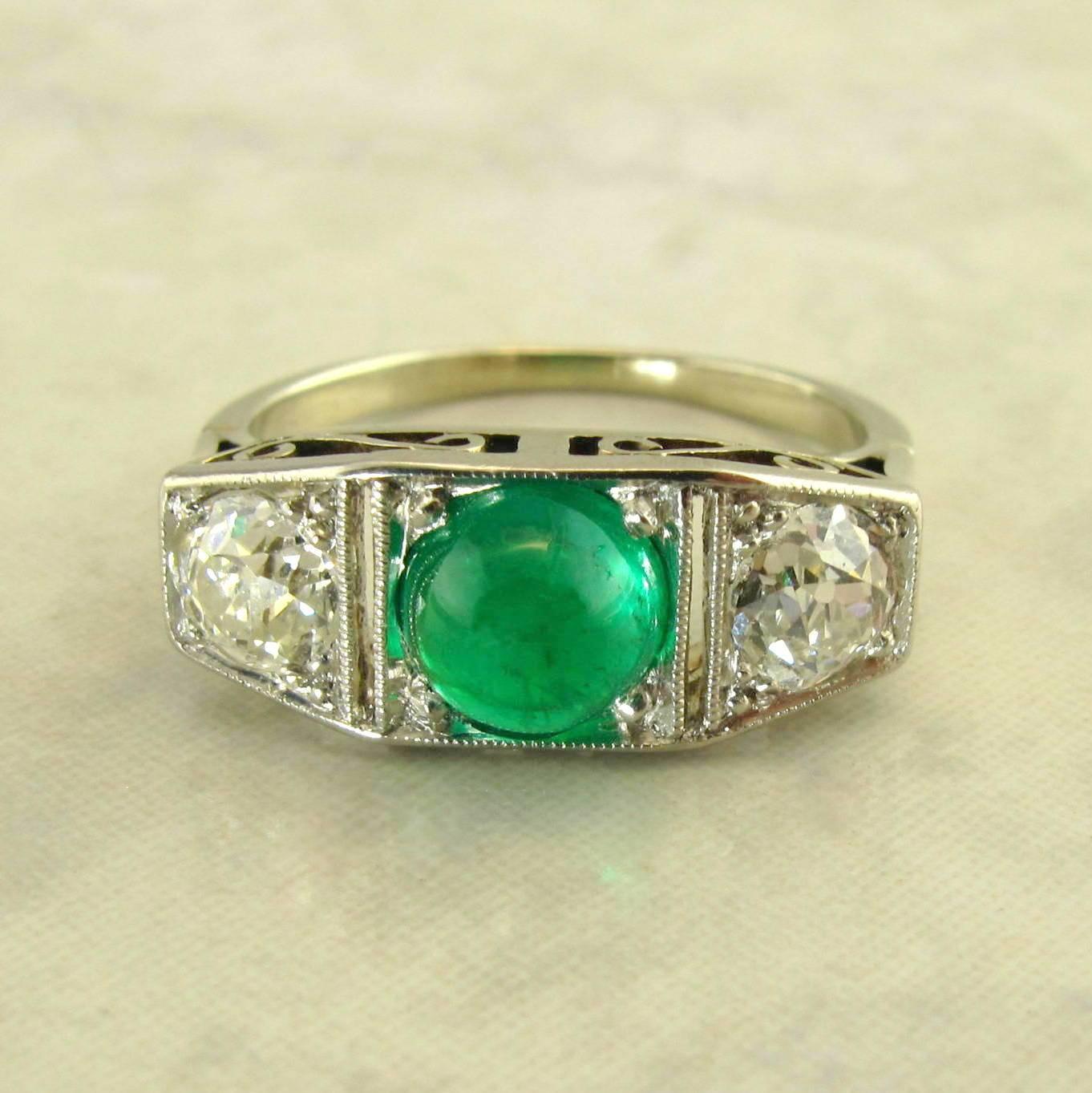 Platinum Art Deco Emerald and Diamond Ring.
The three stone rectangular Art Deco ring set with one center cabachon cut emerald weighing approximately 1.00 carats, accented by two old mine cut diamonds weighing approximately .80 carat total, with